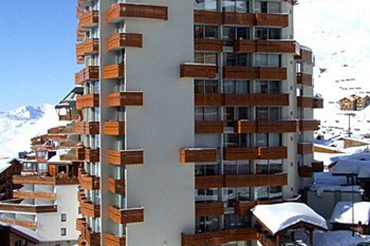 A building with a lot of balconies is covered in snow