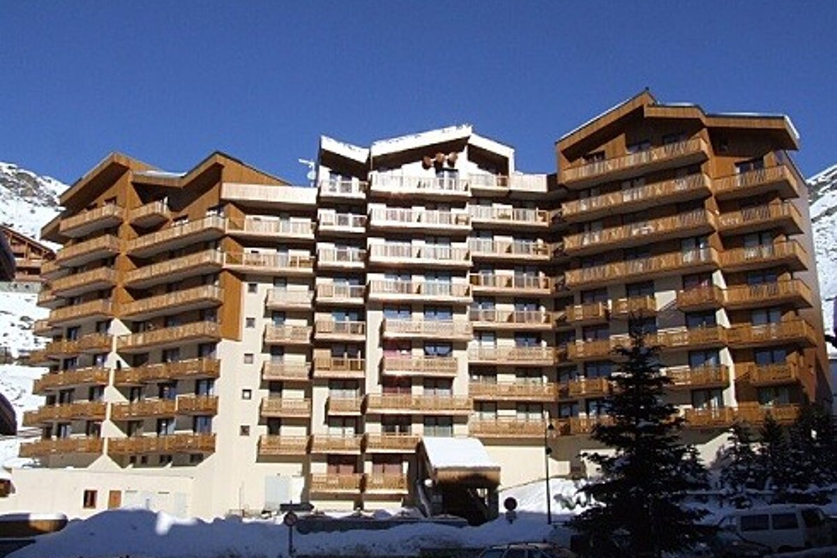 A large building with a lot of balconies is covered in snow