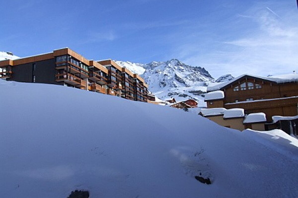 Snow covered buildings with mountains in the background