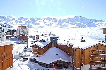 Snow covered buildings in a ski resort with mountains in the background