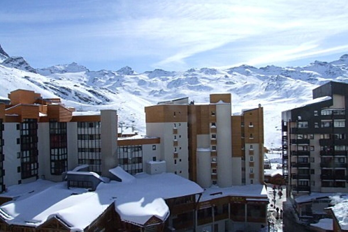 Snow covered buildings in a ski resort with mountains in the background