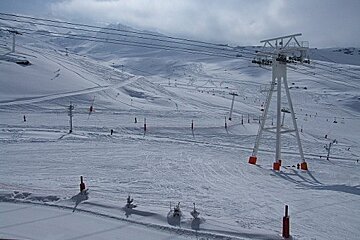 A ski lift going up a snow covered slope