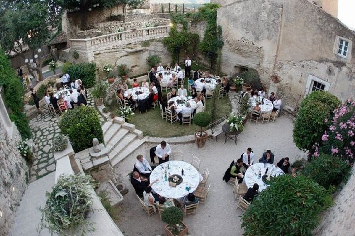 A group of people are sitting at tables in a courtyard