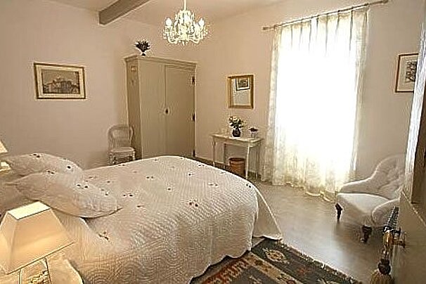 A bedroom with a bed , chairs , lamps and a chandelier