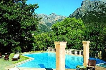 A large swimming pool surrounded by trees and chairs with a mountain in the background