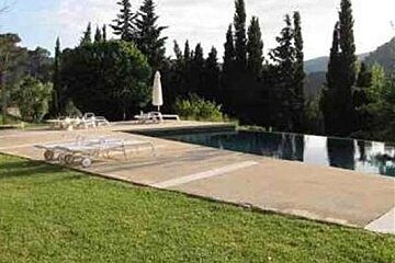 There is a large swimming pool in the middle of a lush green field
