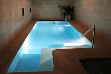an image of an indoor swimming pool with a stone wall around it