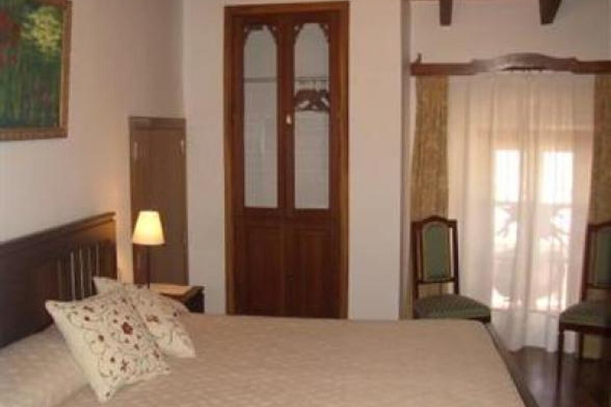 an image of a bedroom with cream covers and patterned cushions