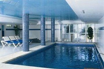 an image of an indoor swimming pool and some loungers next to it