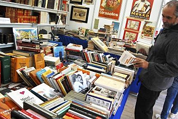 a man browsing books in a white tent