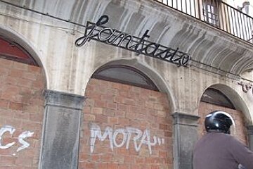 A man is riding a motorcycle in front of a building with graffiti on it