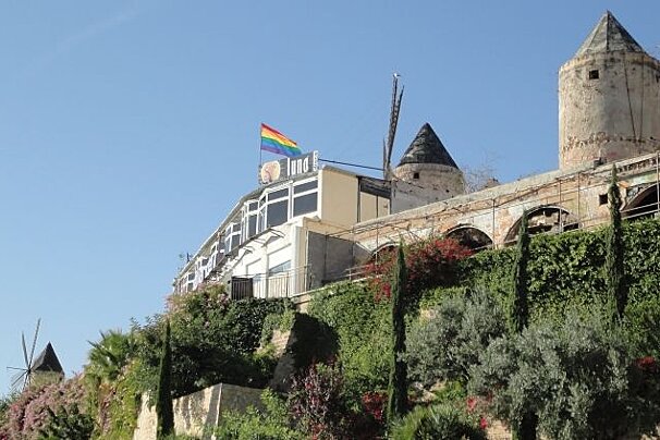 Photo of windmills on hill with rainbow flag