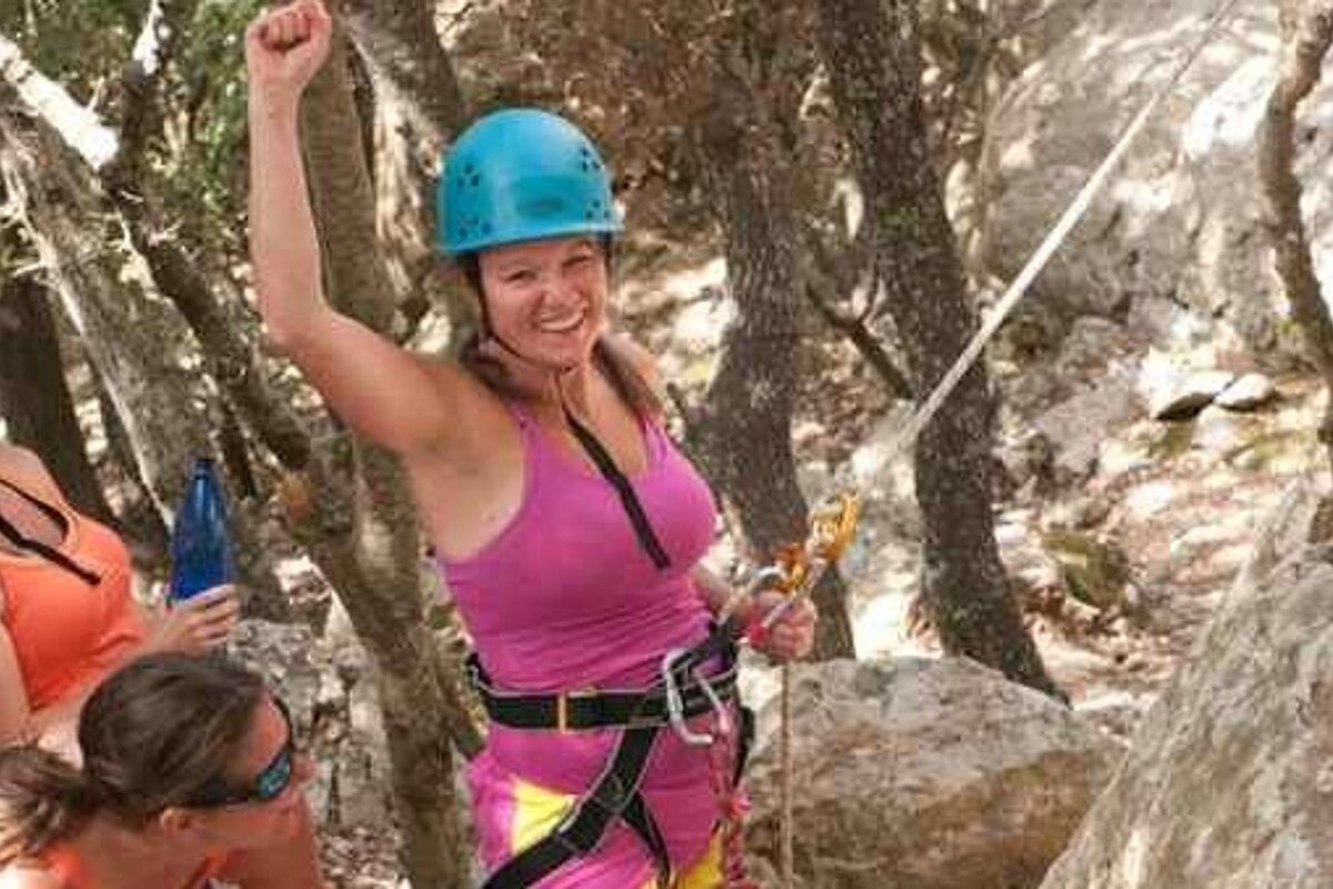 A woman wearing a helmet is climbing a rock wall