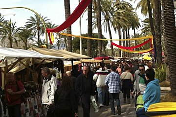 A crowd of people walking down a street with palm trees in the background