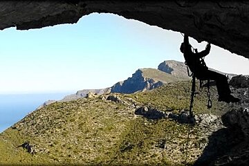 a photo of a man climbing a rock arch