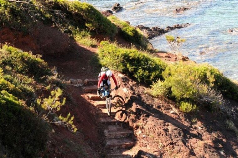 a photo of a mountain biker on steps by the sea