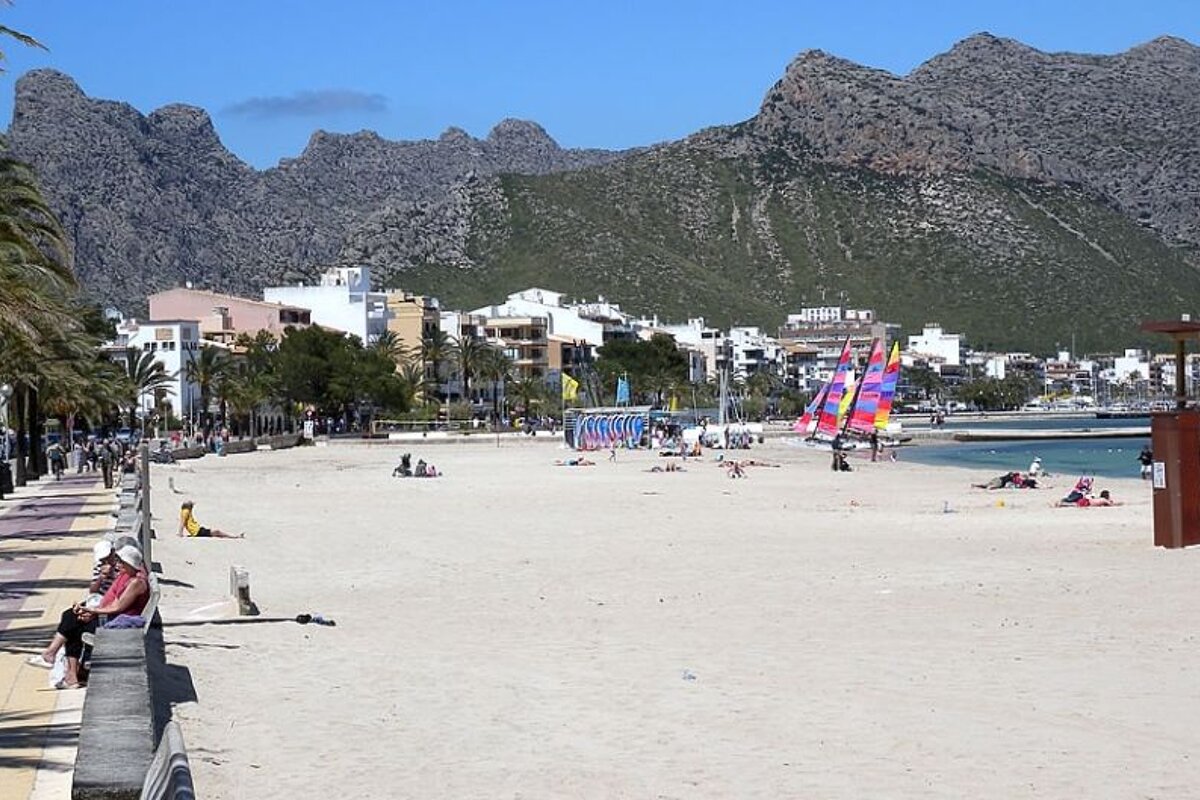 photo of a white sand beach with mountains in the background