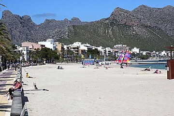 photo of a white sand beach with mountains in the background