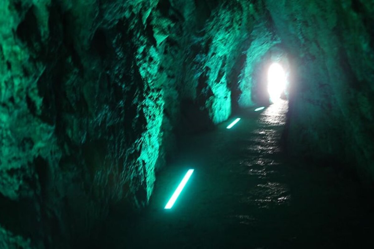 photo of a tunnel in rock lit by green light