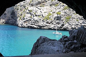 photo of a yacht in blue sea and rocks