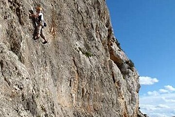 A man is climbing up the side of a large rock wall