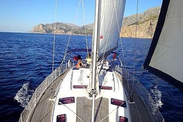 an image of the deck of a sailing yacht in on a flat sea with the Mallorca coastline in the background