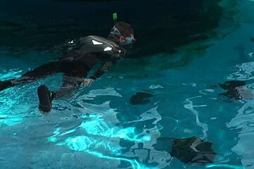 A man is swimming in a pool with stingrays