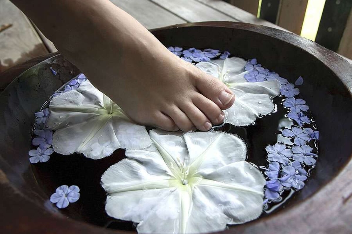 a photo of a foot in a bath with flowers
