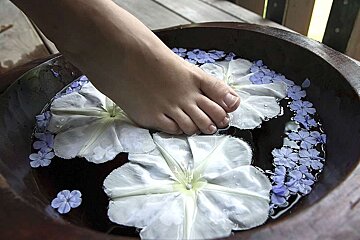 a photo of a foot in a bath with flowers