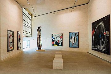 A large room with paintings on the wall and a statue in the middle