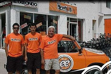 an image of 3 men in orange tshirts stood by an orange car