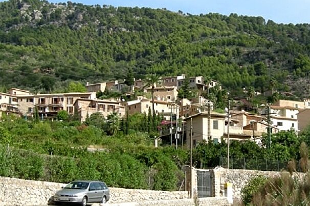 A car is parked on the side of the road in front of a mountain