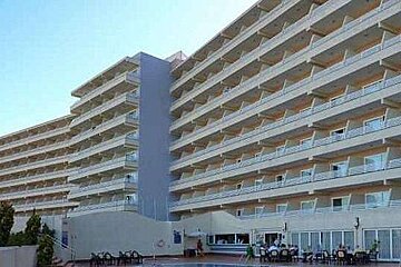 A large building with a lot of balconies and a pool in front of it