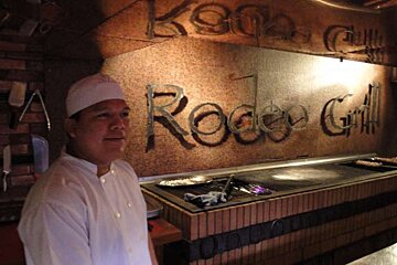 Photograph of chef infront of grill and Rodeo sign