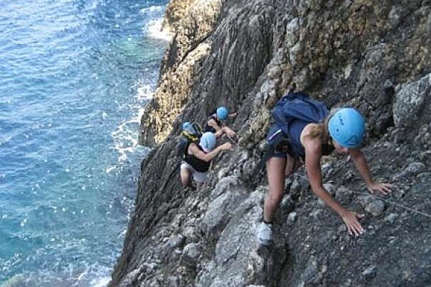 a photo of people climbing up a sea cliff