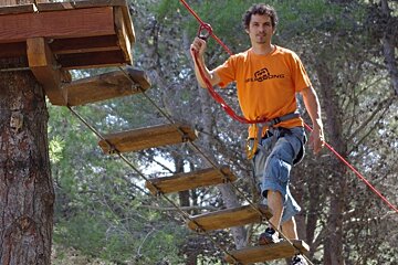 Walking a rope bridge suspended between two trees