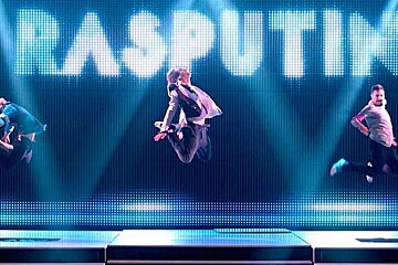 dancers jumping in the air behind Rasputin sign