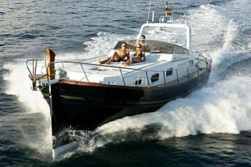 an image of a blue hulled motor boat cutting through the sea with sunbathers on deck