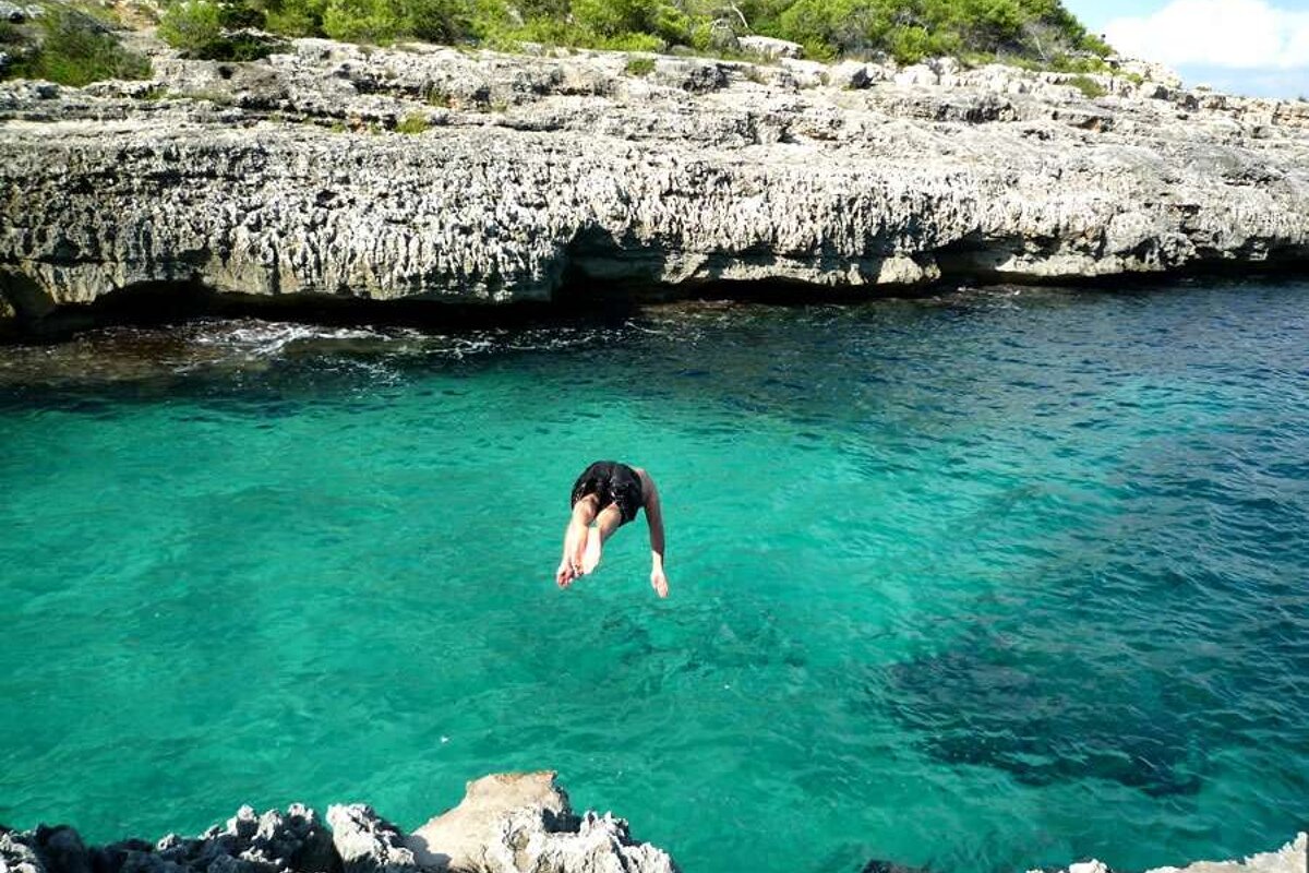 a photo of a man diving into the sea in majorca
