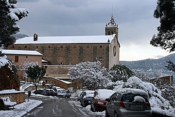 Church in snow with snow covered cars in the foreground