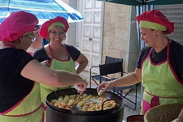 three women preparing bunuelos at a fair