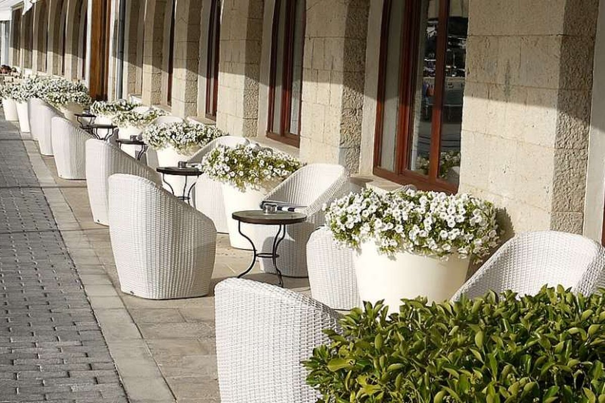 photo of a pavement cafe with white chairs and white flowers