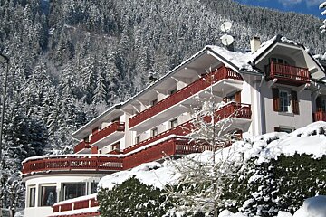 A large white building with red balconies is covered in snow
