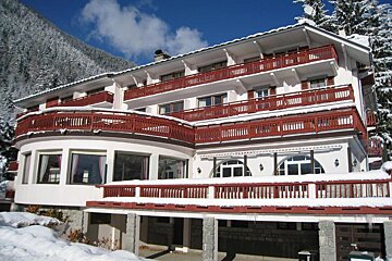 A large white building with red balconies is covered in snow
