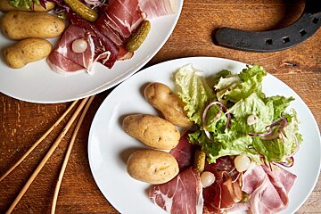 A plate of meat and potatoes sits on a wooden table