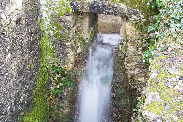 A waterfall is coming out of a hole in the rocks