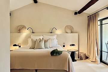A bedroom with a bed and two lamps on the wall