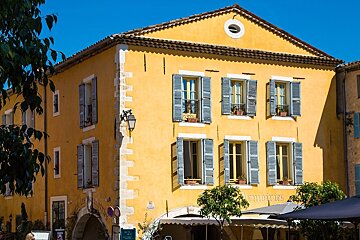 A yellow building with blue shutters and a sign that says 
