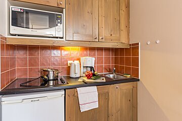 A small kitchen with a brandt refrigerator and a microwave