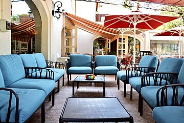 A patio area with blue furniture and red umbrellas